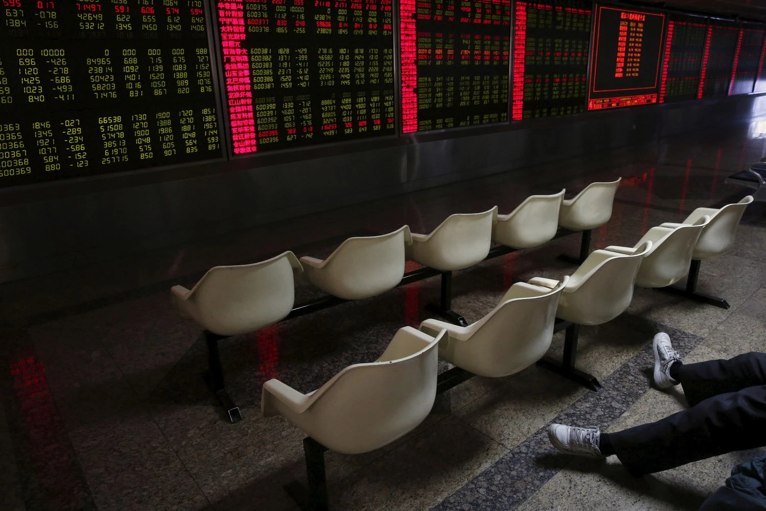 FILE PHOTO: A man's legs are pictured as he looks at an electronic board showing stock information is pictured at a brokerage house in Beijing, China, January 5, 2016. REUTERS/Kim Kyung-Hoon/File Photo