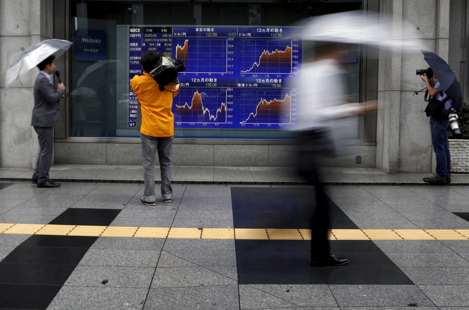 Videographer films an electronic board showing the graphs of exchange rates between the Japanese yen, the U.S. dollar and Euro outside a brokerage in Tokyo, Japan, July 6, 2015. The euro and stock prices fell sharply in Asia on Monday after the Greeks had overwhelmingly rejected austerity measures demanded in return for bailout money, putting in doubt its continued place in the single currency. U.S. equity futures dropped around 1.4 percent while Japan's Nikkei shares fell 1.4 percent and MSCI's broadest index of Asia-Pacific shares outside Japan dropped 0.5 percent. REUTERS/Yuya Shino