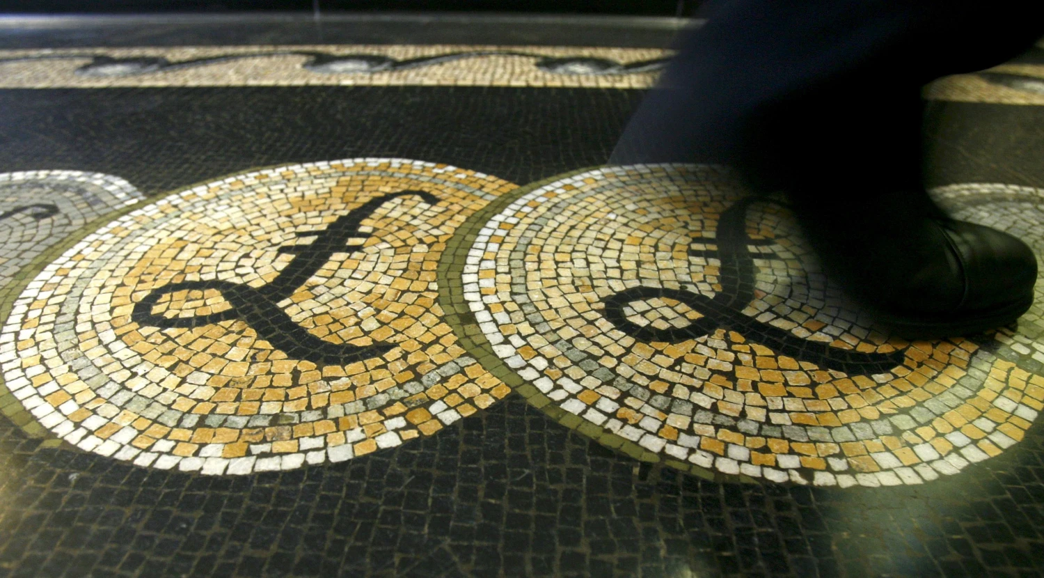 An employee is seen walking over a mosaic of pound sterling symbols set in the floor of the front hall of the Bank of England in London, in this March 25, 2008 file photograph.   REUTERS/Luke MacGregor/File Photo