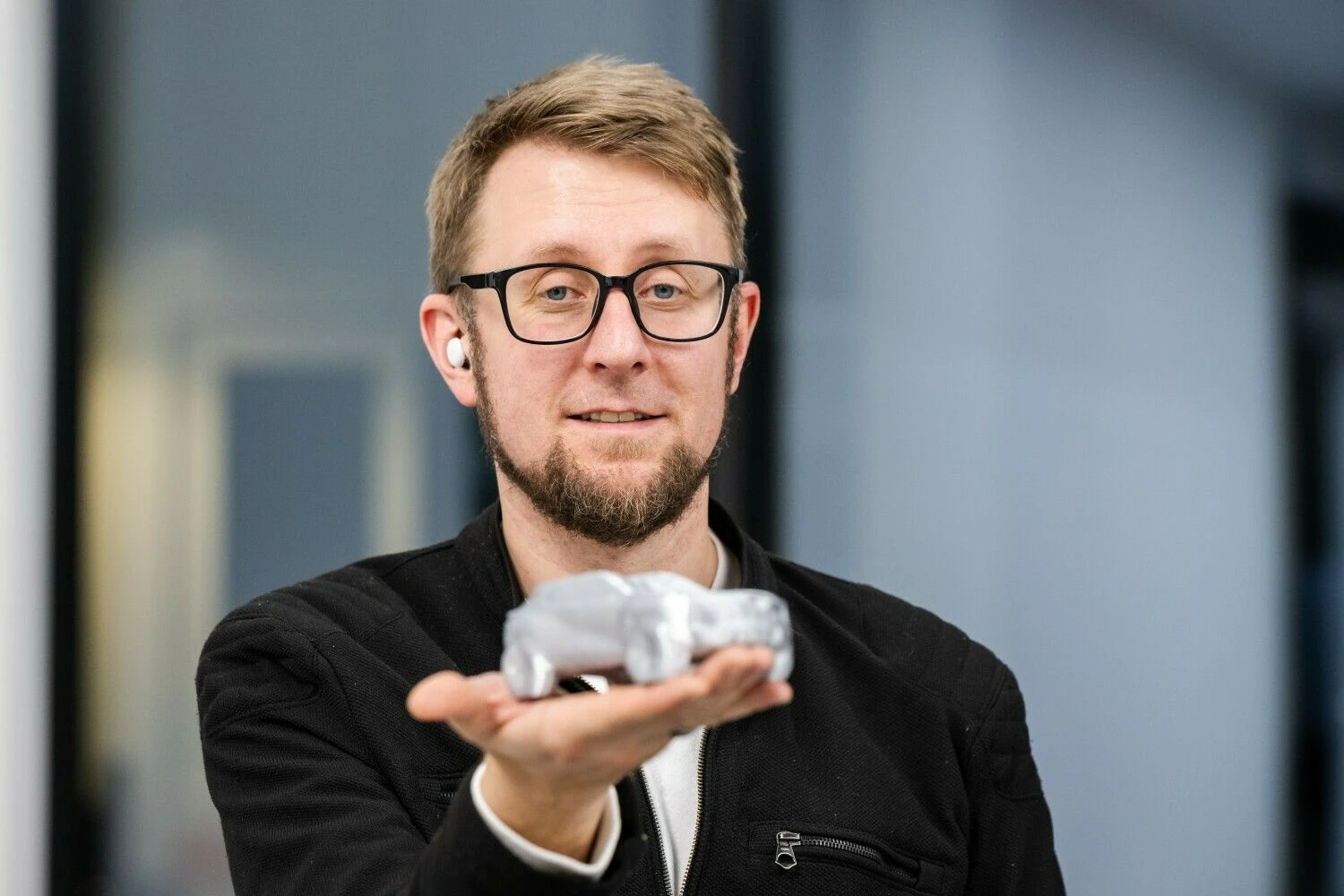 Automobilių dizaineris Tomas Jankauskas rankose laiko DI sugeneruotą ir trimačiu spausdintuvu išspausdintą automobilio miniatiūrą. Vytauto Pilkausko nuotr.