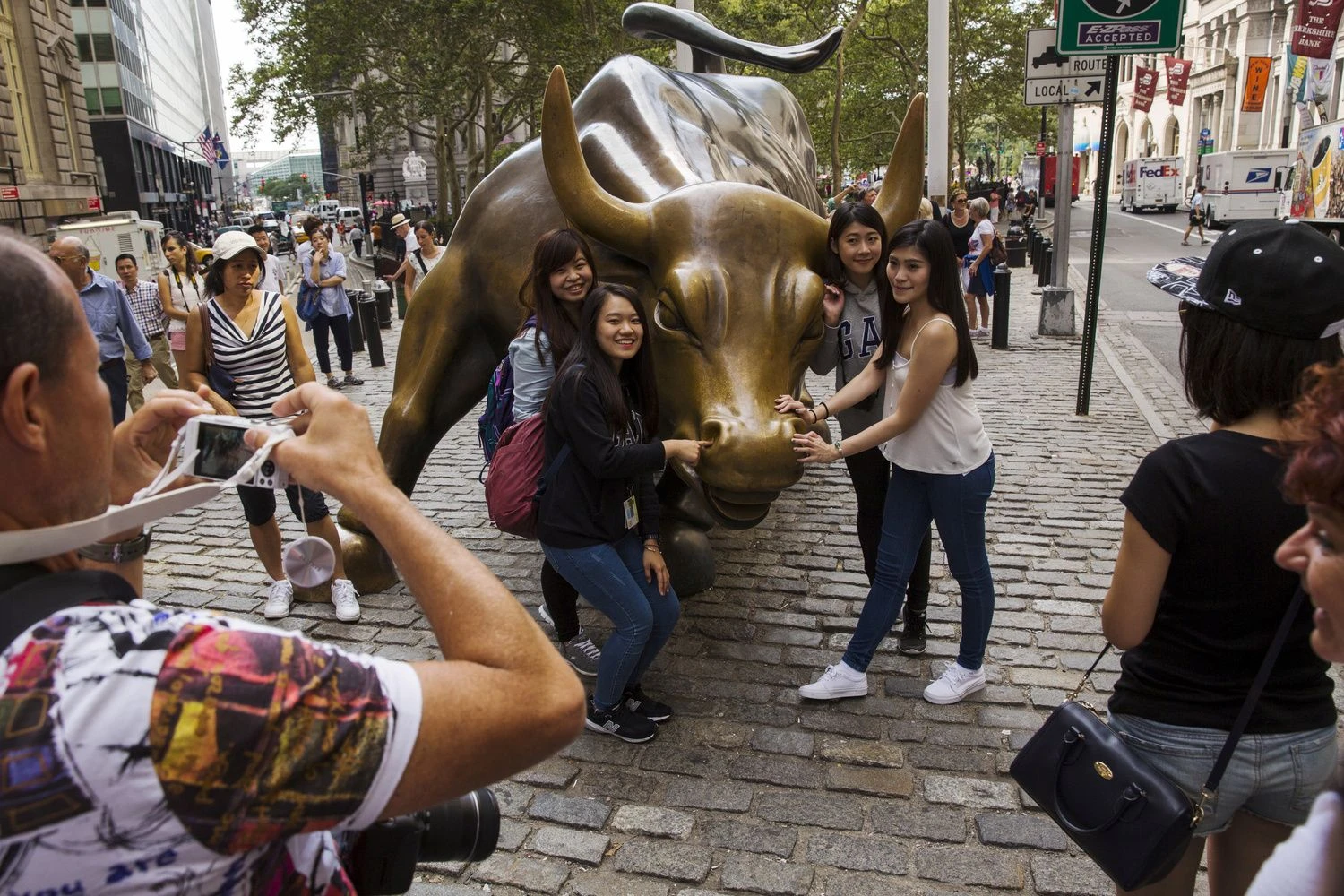 FILE PHOTO: Chinese tourists pose for photographs with a landmark statue of a bull in New York August 24, 2015. This Wednesday, the S&P 500's  bull-market run will turn 3,453 days old, which in some market watchers' eyes will make it the longest such streak in history. The debate is when, not if, the run comes to an end.  REUTERS/Lucas Jackson/File Photo