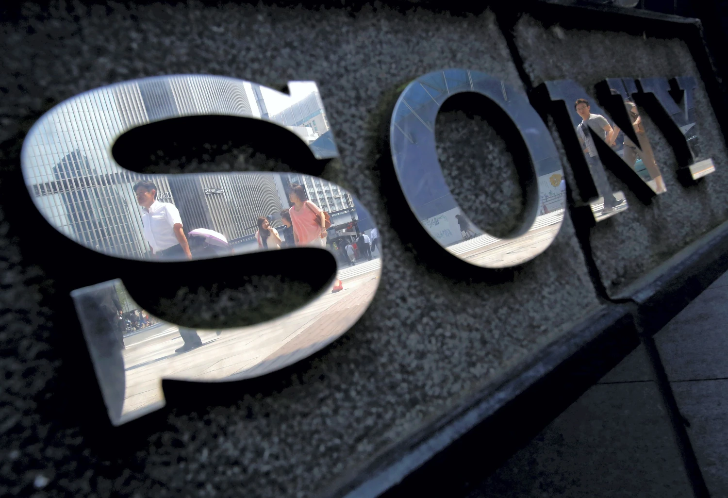 Pedestrians are reflected in a logo of Sony Corp outside its showroom in Tokyo, Japan, June 23, 2015. REUTERS/Yuya Shino