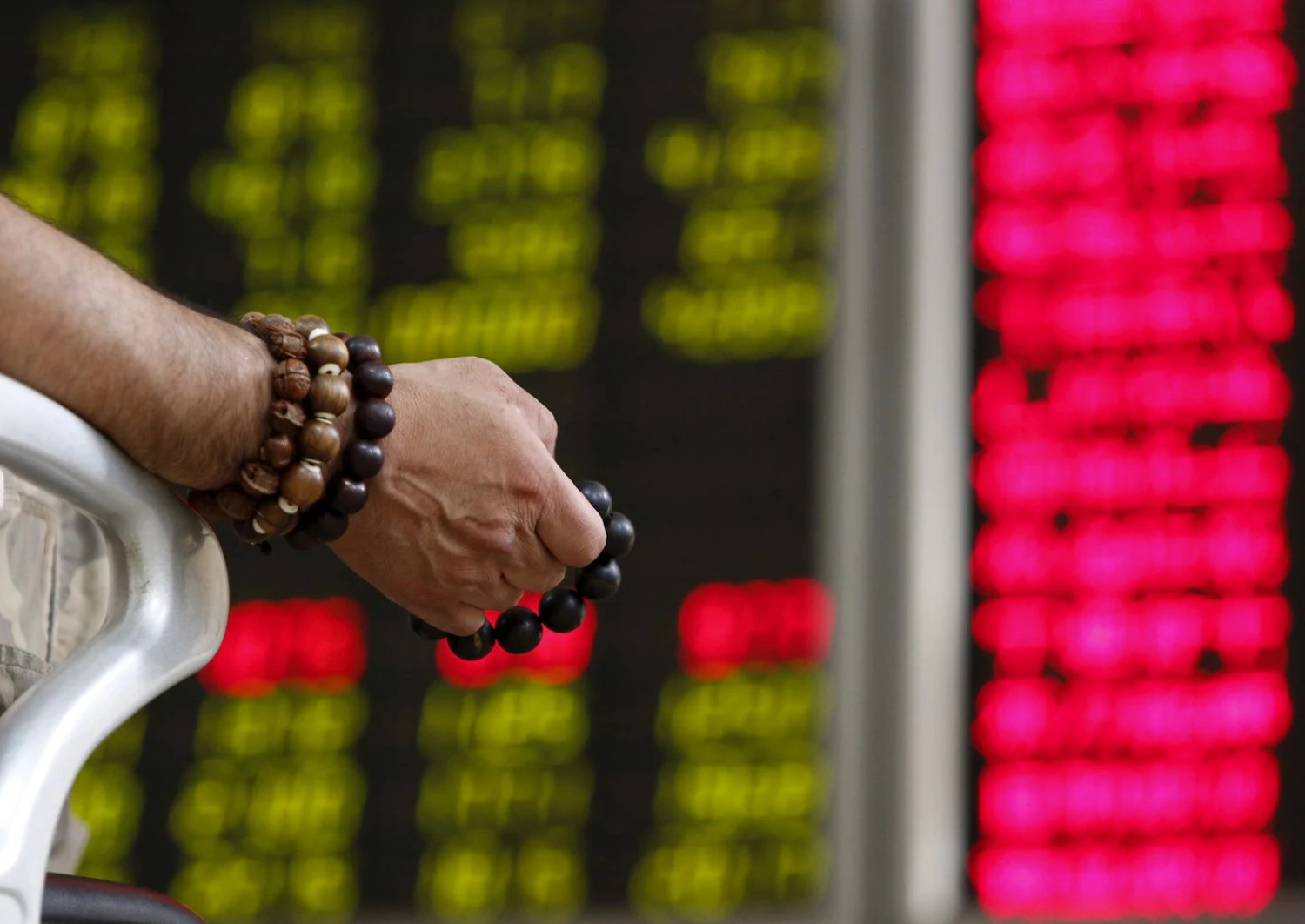 FILE PHOTO: An investor holds onto prayer beads as he watches a board showing stock prices at a brokerage office in Beijing, China, July 6, 2015.  REUTERS/Kim Kyung-Hoon/File Photo
