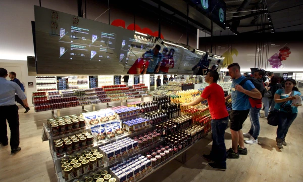 „Future Food District“ ateities prekybos centre „Expo“. Interaktyvus, tamsokas, labiau primenantis kino salę, o ne maisto parduotuvę. Dėmesio maistui neskiriantį, skubantį, tik kainą matantį pirkėją šis multimedijos prikimštas prekybos žaisliukas sunervins.  Pietro Baroni („Expo 2015“) nuotr.

Žvaigždelėmis išmarginto amerikietiško „food track“ – maisto sunkvežimio – maisto snobai turėtų lenktis iš tolo. Bet nereikia skubėti daryti išvadų – „Expo“ stebina ir nustebina.

Pauliaus Jurkevičiaus nuotr.