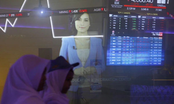 Indonesian student walk in front of an Indonesia Stock Exchange board in Jakarta, June 12, 2013. Asian stock, bond and currency markets took another big hit on Tuesday after a fresh spike in U.S. interest rates re-ignited concerns about capital flows from the region and prompting a surprise rate hike by Indonesia's central bank. REUTERS/Beawiharta (INDONESIA - Tags: BUSINESS)