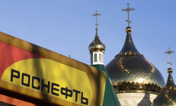 The logo of Russia's top crude producer Rosneft is seen on a gasoline station near a church in Stavropol, southern Russia, December 9, 2014. REUTERS/Eduard Korniyenko 