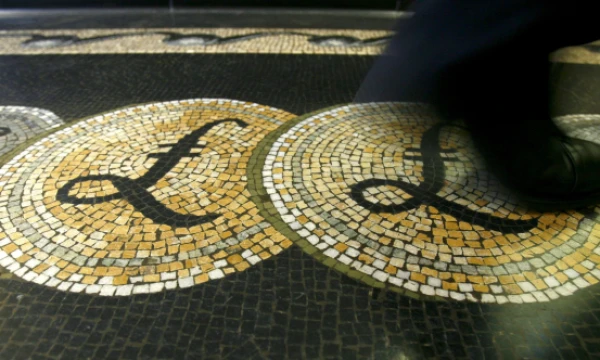 An employee is seen walking over a mosaic of pound sterling symbols set in the floor of the front hall of the Bank of England in London, in this March 25, 2008 file photograph.   REUTERS/Luke MacGregor/File Photo
