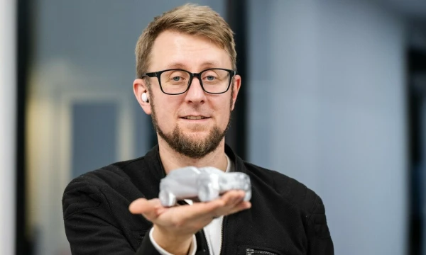 Automobilių dizaineris Tomas Jankauskas rankose laiko DI sugeneruotą ir trimačiu spausdintuvu išspausdintą automobilio miniatiūrą. Vytauto Pilkausko nuotr.