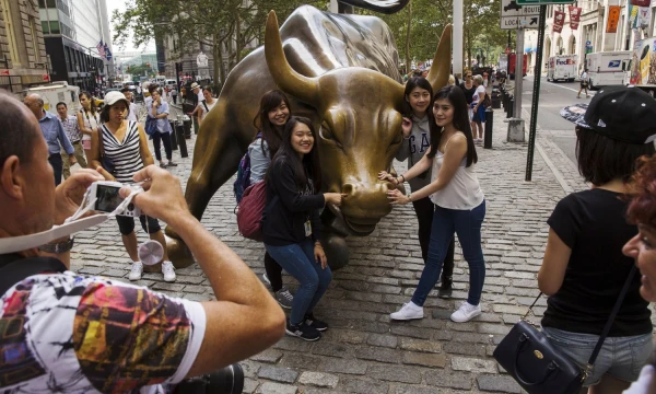 FILE PHOTO: Chinese tourists pose for photographs with a landmark statue of a bull in New York August 24, 2015. This Wednesday, the S&P 500's  bull-market run will turn 3,453 days old, which in some market watchers' eyes will make it the longest such streak in history. The debate is when, not if, the run comes to an end.  REUTERS/Lucas Jackson/File Photo