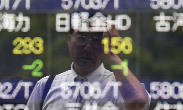 A man wipes his head as he is reflected on a stock quotation board outside a brokerage in Tokyo June 10, 2014. Asia stocks nudged three-year highs on Tuesday on rising optimism over global growth prospects and a record-run on Wall Street, helping lift Treasury yields and the dollar. REUTERS/Issei Kato (JAPAN - Tags: BUSINESS)