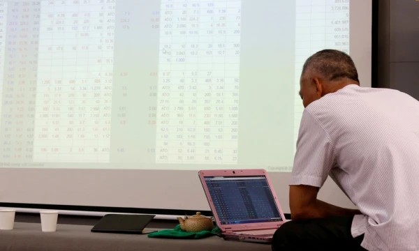 FILE PHOTO: An investor looks at a screen showing stock board information at a securities company in Hanoi, Vietnam July 6, 2018. Picture taken July 6, 2018. REUTERS/Kham/File Photo